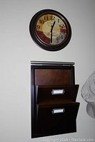 Wall clock mounted above the mail wall organizer showing size and design details.