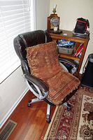 Leather office chair angled with one decorative pillow on the seat.