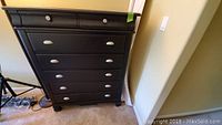 Front view of black 7-drawer chest showing all drawers and metal cup pull handles.