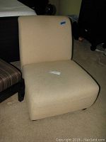 Front view of one beige fabric low sitting chair showing its upholstery and overall shape.