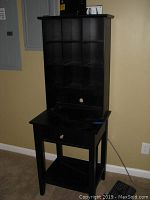 Front view of the black wooden mail stand showing nine cubby slots, drawer, and bottom shelf.