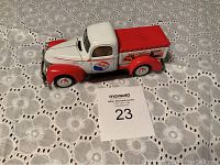 Side angle view of collectible Pepsi Cola metal truck model with visible Pepsi logos and detailed truck features on white lace tablecloth.