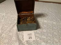 Chest with hinged lid open showing large number of wheat pennies inside on a lace tablecloth.