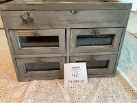 Front view of a rustic wooden display case with four glass-front drawers and round metal knobs.