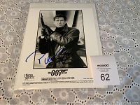 Black and white promotional photo of Pierce Brosnan as James Bond, signed by him in blue ink.