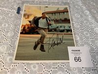 Signed photograph of Keanu Reeves mid-run with explosion background and large black autograph