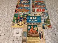 Overview photo showing the seven comic books stacked and spread out on a lace cloth background with lot number tag.