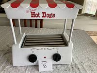 Front view of white and red Nostalgia Electrics hot dog roller with five rollers and control dials.