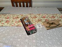 Photo showing the 39x11 inch runner, Barbie Fashionistas doll in package, and Hopes and Dreams blank book on a wooden chair.