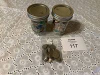 Photo showing two half pint mason jars with metal lids; one filled with marbles, one filled with stamps, and a labeled plastic bag with 40 no date Buffalo nickels on a lace tablecloth.