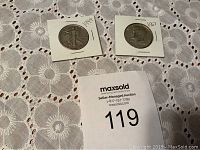 Two half dollars in protective holders on a lace table cloth. Left is the 1944 Walking Liberty, right is the 1967 Lincoln Silver Composition.