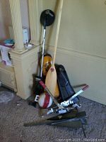 Boat and diving items arranged on floor including wooden paddle, flippers, anchor, buoy, diver tank, treasure detector.