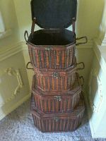 Stacked view of four decorative wicker and wood cases, largest at bottom to smallest on top, showing side handles and latch hardware.
