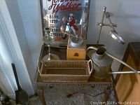 Top view of table with items including watering can, candlestick, coffee grinder, serving tray, and framed sign.