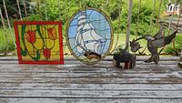 View of all four decorative items together: two stained glass panels and two metal sculptures.