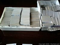 Two white plastic containers filled with rows of cardboard coin flips sorted by country and year