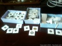 Overview of three boxes with coins in cardboard holders and loose