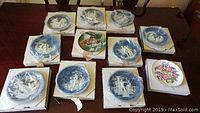 Ten Bradford Exchange and Royal Albert collector plates on table. Plates protected in original boxes and plastic wrap.