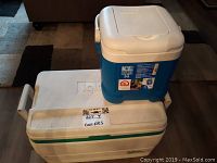 Photo showing large white Igloo cooler with green latch and small blue and white Igloo Ice Cube cooler on top.