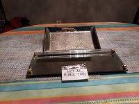Two mirror trays on a striped tablecloth, showing rectangular tray with gold corners and square tray with floral metal plate insert.