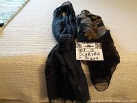 Two scarves displayed on a beige surface with a sign noting lot 13 Scarves & Rings, showing designs and patterns of scarves