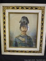 Full view of the framed portrait showing the soldier in military uniform with feathered hat and ornate gold and white frame.