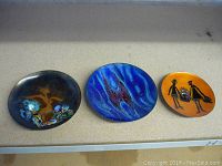 Three vintage MCM enamelled plates displayed, showing size and design variance