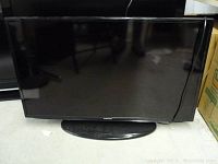 Front view of Samsung 40-inch LED TV with stand, screen off and some reflections visible.