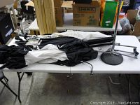 Lot of multiple photography lighting umbrellas and tripods on a table, showing condition and items included