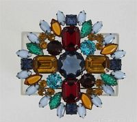 Front view of a large vintage round brooch with colorful glass cabochons in various shapes and colors arranged in a floral/fruit salad pattern.