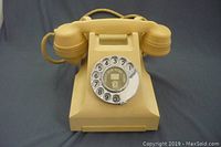 Full view of the beige desk rotary phone with handset in place, showing the geometric Art Deco design and cord attached.