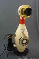 Front view showing bowling pin body, rotary dial, earpiece, receiver, and cable.
