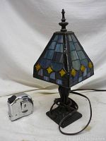 Full view of the lamp next to a tape measure showing its height, black base, and electrical cord.