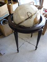 Full view of the approx. 35-inch tall vintage globe on its dark wooden tripod stand with metal braces.