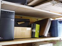 Shelf with ASUS desktop computer tower and various boxes and containers