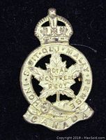 Front view of the vintage Canadian military cap badge featuring a maple leaf and crown, with inscriptions for the Royal Montreal Regiment.