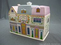 Front and side view of the recipe canister shaped like a village house, showing colorful painted doors, windows and floral decorations, labeled 'Recipes'.
