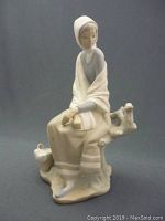 Front angle view of the vintage Lladro-style porcelain figurine showing the seated woman on a naturalistic base, holding a basket with another basket beside her.