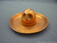 Front angled view of copper ashtray shaped like a Stetson hat showing shape and patina.