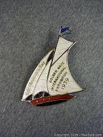 Front view of a vintage metal pin shaped as a sailboat with white sails and brown-red hull, featuring text for the 1939 Golden Gate International Exposition in San Francisco Bay.