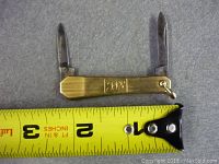 Photo showing pen-knife open with two blades extended and measuring tape indicating approximately 2 1/4 inches in width.