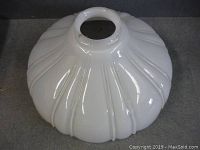 Side view of one white antique glass lampshade showing fluted design and central hole.
