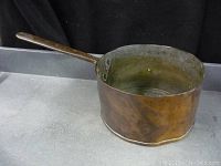 Antique 8.5 inch copper cooking pot with long handle, showing patina and wear on the exterior and interior surfaces.