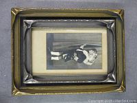 Two antique wooden frames stacked, one with a vintage photo of a child in costume inside the frame.
