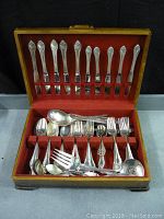 Photo of open wooden case with red velvet lining displaying silver plated cutlery set mostly Rogers Remembrance pattern.