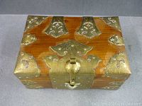 Top full view of box showing wood and brass accents including corner plates and Turtle lock plate on front.