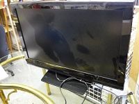 Full frontal view of the Toshiba television on stand, showing black frame and screen reflective surface.