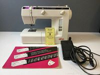 Full view of white Elna 2004SP sewing machine, instruction manual, and foot pedal on table with Maxsold lot tag.