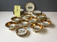 Full view of the tea set showing cups, saucers, cake plates, and tea bag dishes arranged with gold edging and castle designs inside cups.