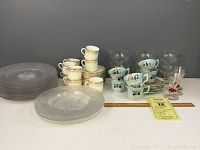 Photo showing the full lot including etched dessert plates stacked on the left, Adams demitasse cups stacked beside them, six clear molded sherbet glasses in back, and Mintons demitasse cups and saucers with turquoise and floral decoration in front right.